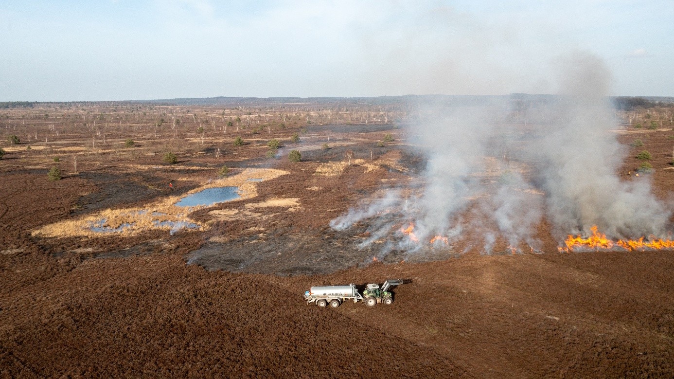 Luftaufnahme beim Heidebrand: Brennende Heidefläche und Wasserwagen